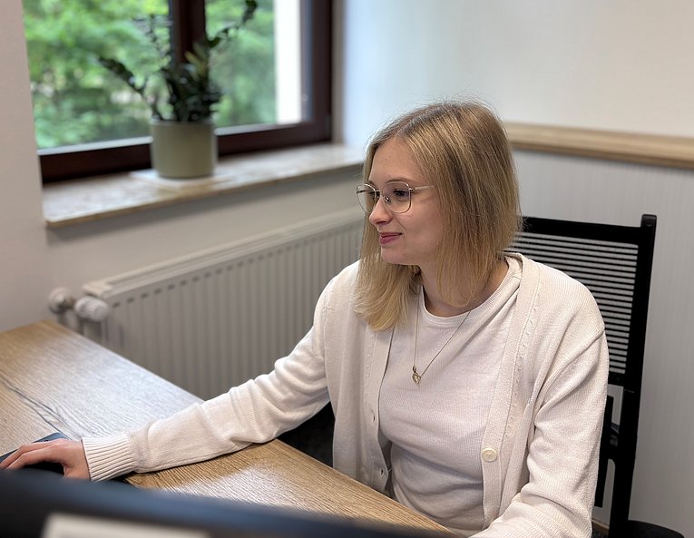 Emely Hofbauer_Azubine_Kauffrau Büromanagement Junge Frau sitzt am Schreibtisch und arbeitet konzentriert am Computer