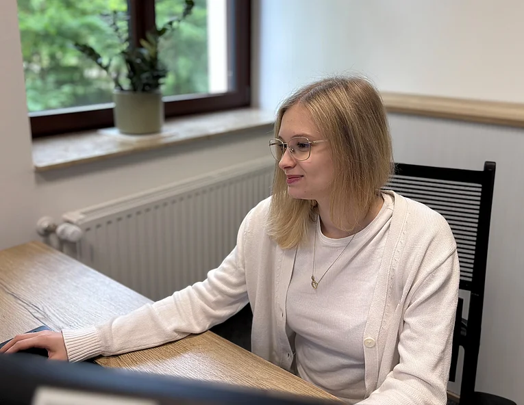 Junge Frau sitzt am Schreibtisch und arbeitet konzentriert am Computer